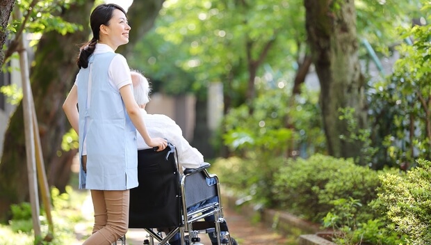 車椅子に乗った入居者をスタッフが押しながら外を散歩する様子