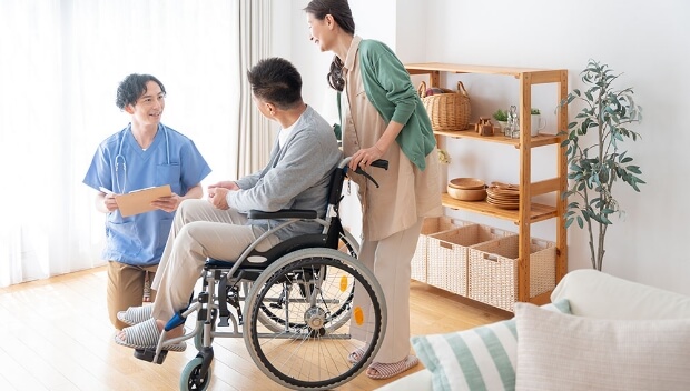 居室にて、車椅子に乗った入居者とその家族がスタッフから説明を受ける様子