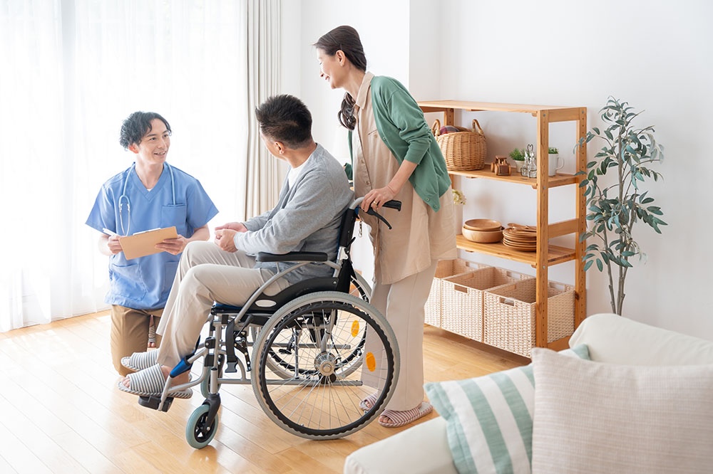 居室にて、車椅子に乗った入居者とその家族がスタッフから説明を受ける様子